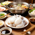 Small cuttlefish simmering in a hot pot broth with vegetables and chopsticks