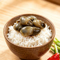 Marinated shellfish served over steamed rice in a rustic wooden bowl